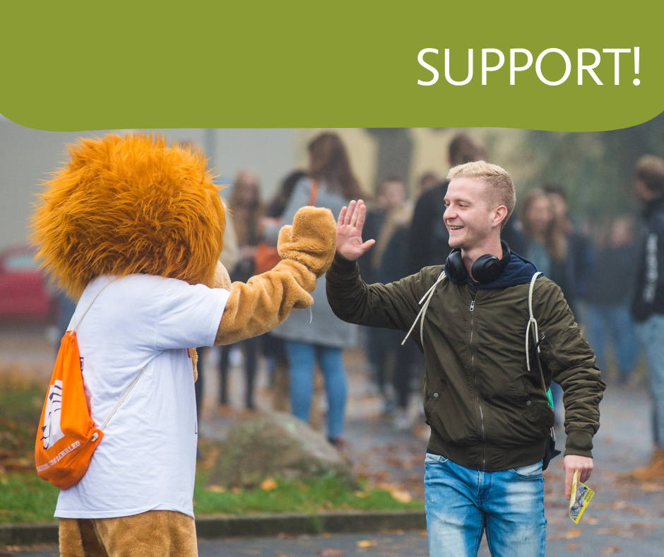 A student highfives the lion mascot of the TU Braunschweig.