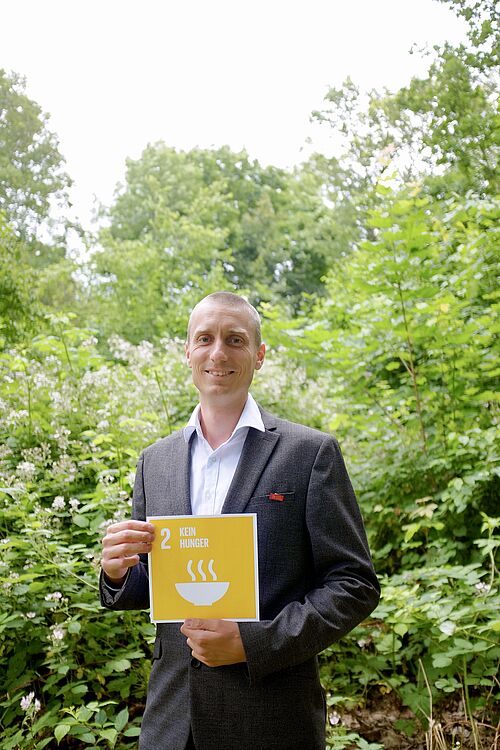 Prof. Dr. Boas Picker hält eine Karte mit SDG 2