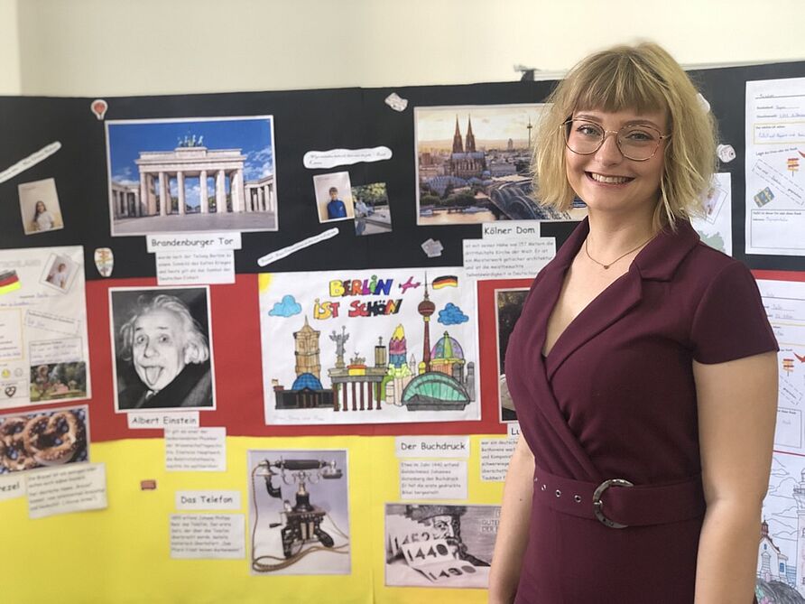 Student Michaela Görg stands in front of a pinboard on which information about Germany is pinned. 