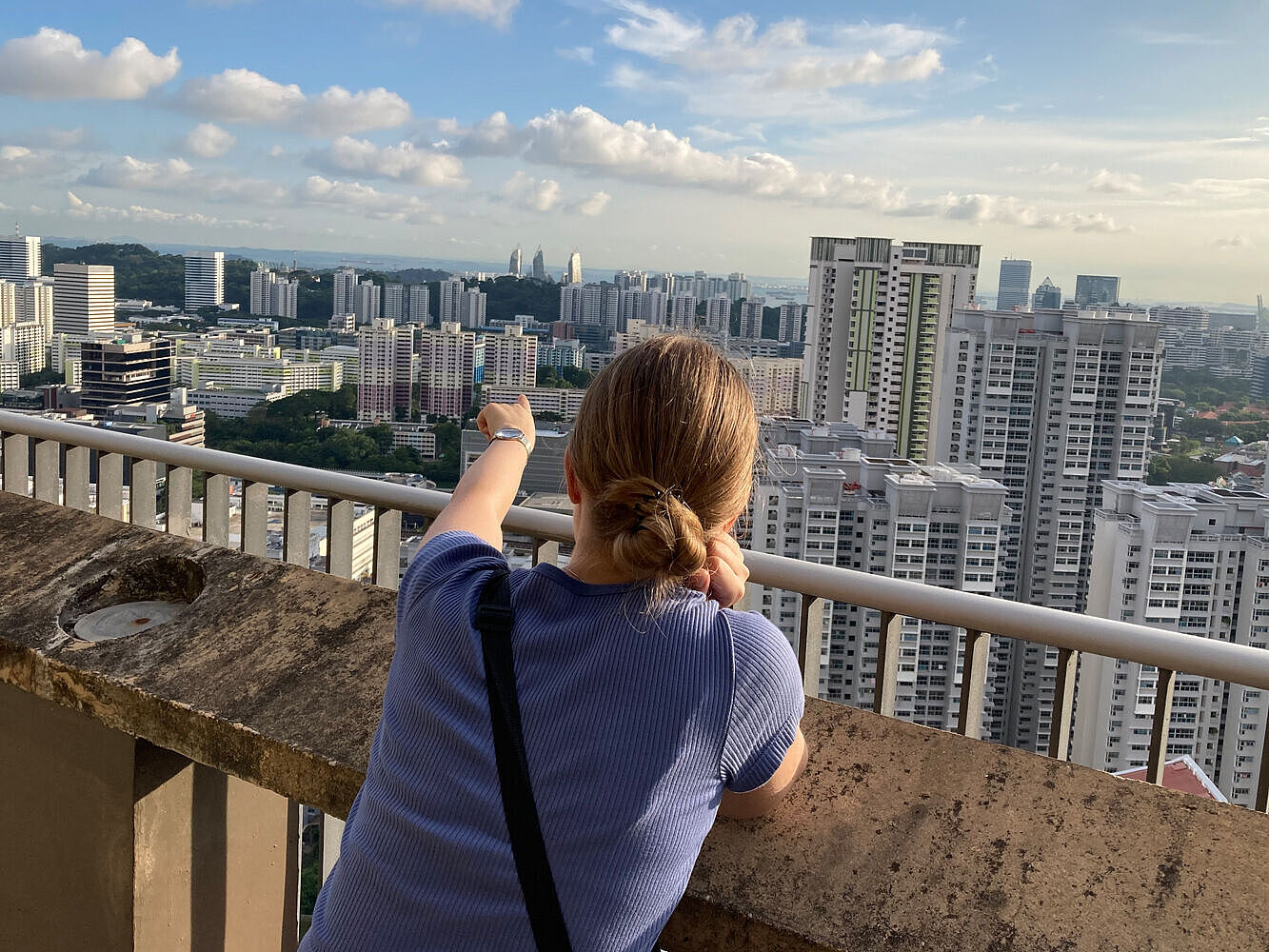 The student stands on top of a residential building in Queenstown and enjoys the view over the city of Singapore. 