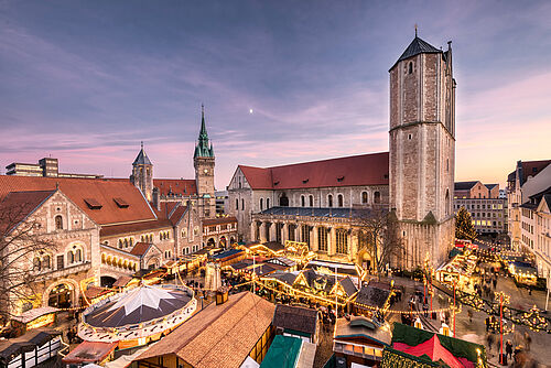 Blick auf den beleuchteten Braunschweiger Weihnachtsmarkt in der Abenddämmerung.