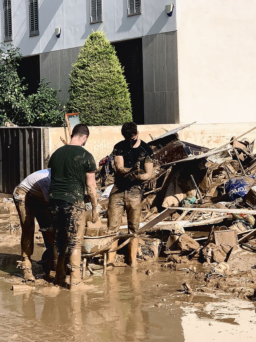 Massanassa: Drei Personen bringen eine Schubkarre, gefüllt mit zerstörtem Mobiliar, aus dem Keller eines Hauses