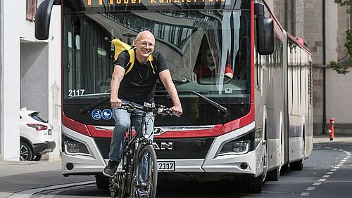 Prof. Mark Vollrath auf einem Fahrrad ohne Helm, im Hintergrund ein Linienbus