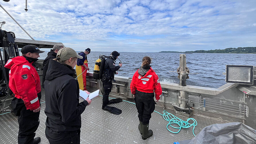 Researchers stand with a diver on a research boat.