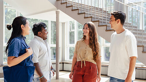 Vier Studierende stehen im Eingangsbereich des Altgebäudes der TU Braunschweig und unterhalten sich.