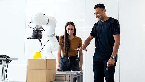 Eine Frau und ein Mann stehen vor einem Roboterarm